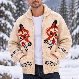 May include: A cream-colored, chunky knit zip-up cardigan featuring a prominent fox motif on the chest in shades of orange, black, and red. The garment includes a ribbed collar, ribbed cuffs, two front pockets, and a full-length metal zipper closure.