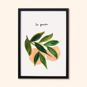 May include: A framed art print with a watercolour illustration of peaches and green leaves. The artwork includes the handwritten text "la peche" in black. The peaches are a soft peach colour, and the leaves are various shades of green.