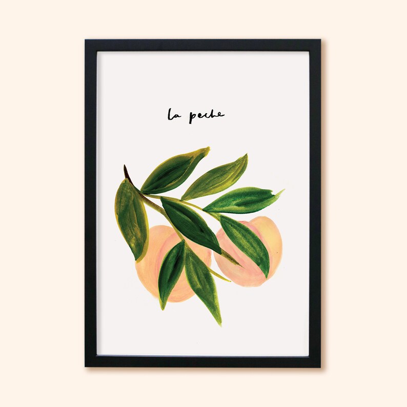 May include: A framed art print with a watercolour illustration of peaches and green leaves. The artwork includes the handwritten text "la peche" in black. The peaches are a soft peach colour, and the leaves are various shades of green.