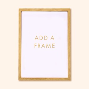 May include: A rectangular wooden picture frame with a light wood grain finish. The white interior has the words "ADD A FRAME" in gold lettering. The frame is designed to hold a picture or artwork.