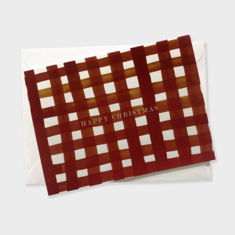 May include: A Christmas card with a red and white plaid pattern and the words "HAPPY CHRISTMAS" in gold lettering. The card is inside a white envelope.