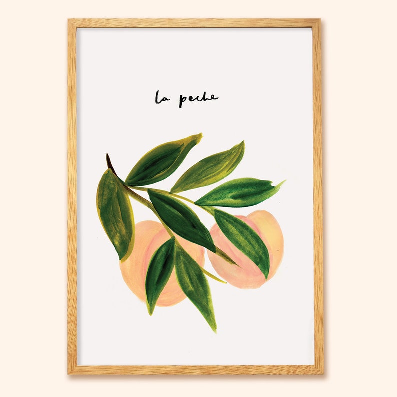 May include: Framed art print with a watercolour illustration of peaches and green leaves. The handwritten text "la peche" is in black. The print is set in a natural wood frame, suitable for home decor and wall art.