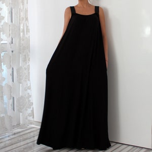 May include: A black sleeveless maxi dress with a simple, loose fit. The dress has thin straps and a scoop neckline.