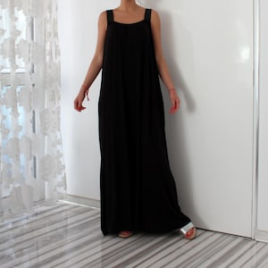 May include: A long black sleeveless maxi dress with thin straps. The dress has a loose, flowing fit and is made of a soft, comfortable fabric.