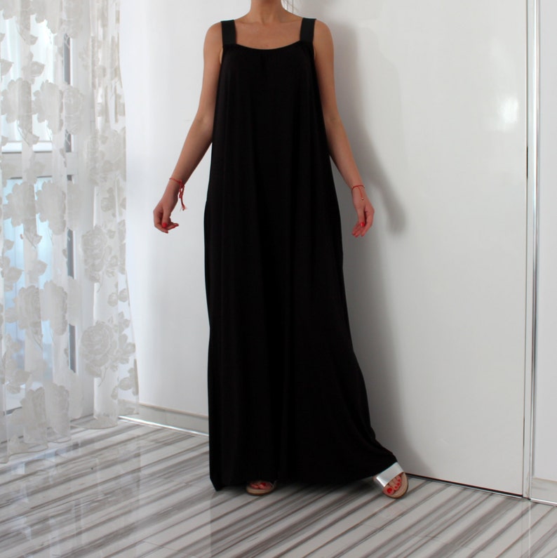 May include: A long black sleeveless maxi dress with thin straps. The dress has a loose, flowing fit and is made of a soft, comfortable fabric.