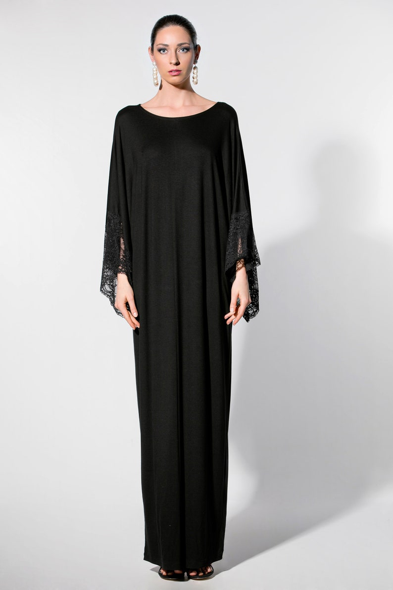 Puede incluir: Vestido negro largo con escote redondo y mangas anchas. Los pu&ntilde;os de las mangas tienen detalles de encaje. El vestido est&aacute; hecho de una tela fluida, ideal para eventos especiales o de noche.