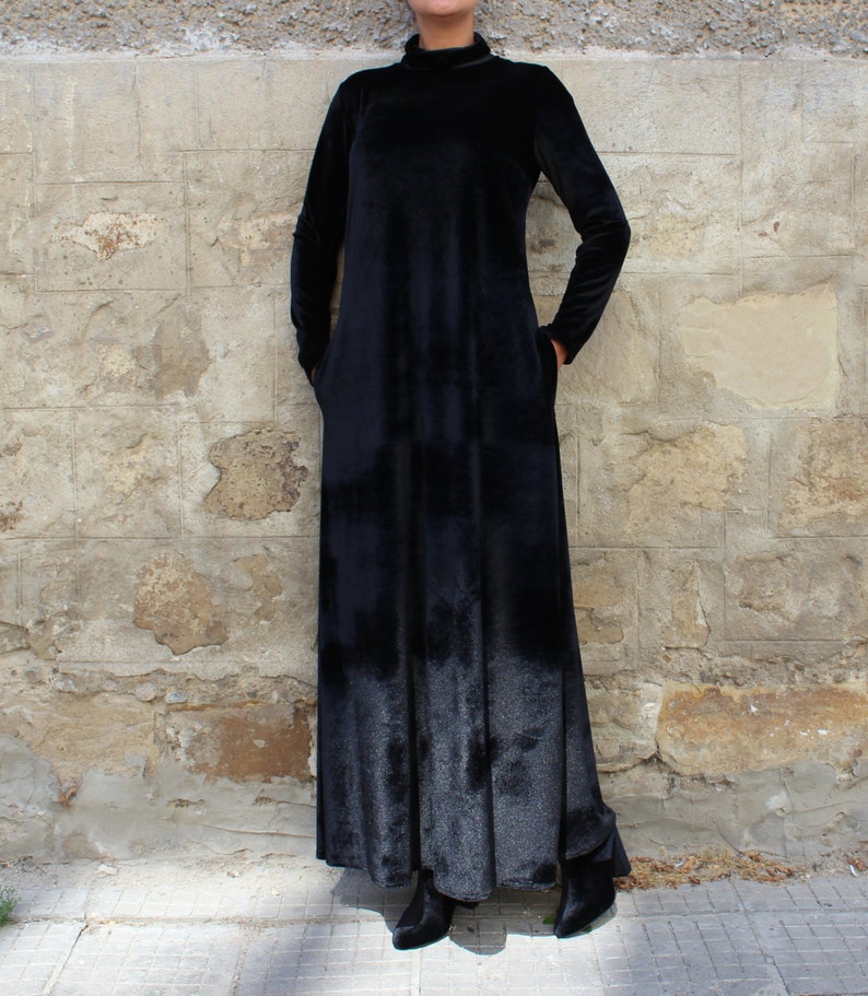 May include: A long black velvet dress with a mock neck and long sleeves. The dress has a loose fit and falls to the ankles.