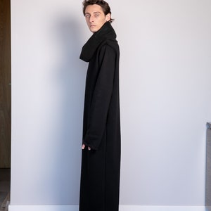 May include: A black long-sleeved hooded dress with a high neck and a relaxed fit. The dress is made of a soft, comfortable fabric and has a long, flowing silhouette.