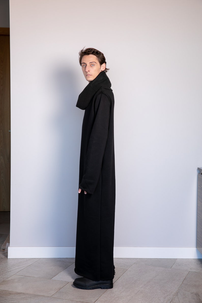May include: A black long-sleeved hooded dress with a high neck and a relaxed fit. The dress is made of a soft, comfortable fabric and has a long, flowing silhouette.