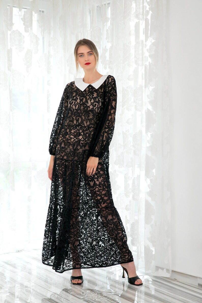 May include: A woman wearing a black lace maxi dress with a white collar and black heels. The dress has a floral pattern and is sheer.