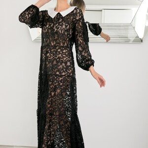 May include: A black lace maxi dress with a white Peter Pan collar. The dress has a sheer, flowing silhouette and is perfect for a special occasion.