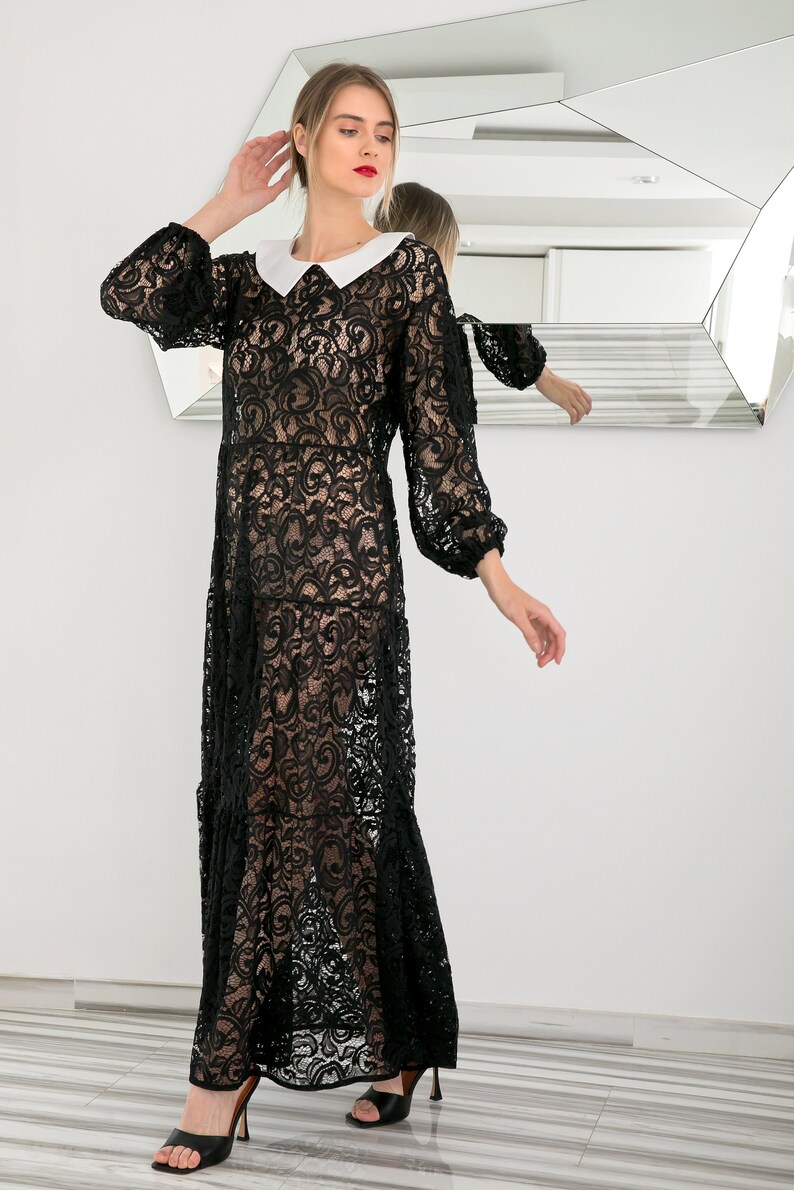 May include: A black lace maxi dress with a white Peter Pan collar. The dress has a sheer, flowing silhouette and is perfect for a special occasion.