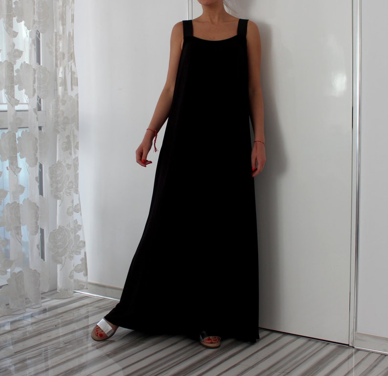 May include: A black sleeveless maxi dress with a square neckline. The dress is made of a soft, flowing fabric and has a relaxed fit.
