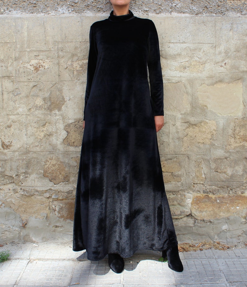 May include: A long black velvet dress with a high neck and long sleeves. The dress has a flowing skirt and is made of a soft, luxurious fabric.