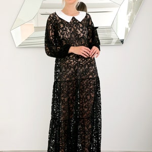 May include: A black lace maxi dress with a white Peter Pan collar. The dress has a sheer, flowing silhouette and is perfect for a special occasion.