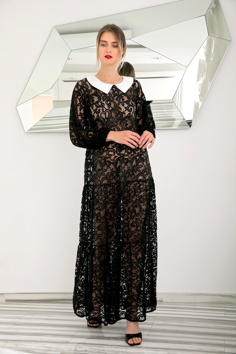 May include: A black lace maxi dress with a white Peter Pan collar. The dress has a sheer, flowing silhouette and is perfect for a special occasion.