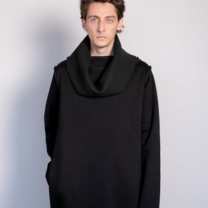 May include: A person wearing a black long-sleeved turtleneck sweater with a cowl neck.