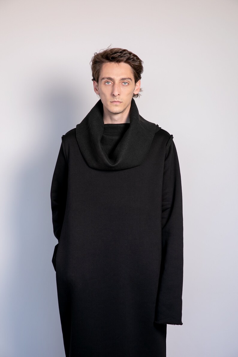 May include: A person wearing a black long-sleeved turtleneck sweater with a cowl neck.