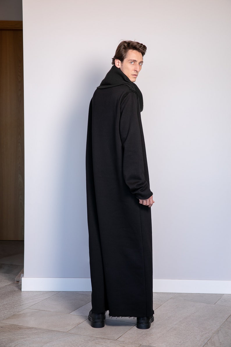 May include: A long black hooded sweater with a high collar and a relaxed fit. The sweater is made of a soft, comfortable fabric and has a slightly distressed hem.