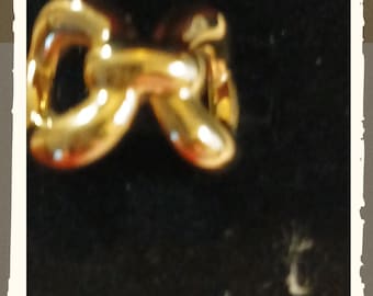 May include: A gold-toned ring featuring a polished, rounded link design. The ring has a smooth, reflective surface with a continuous, interconnected chain-like structure that forms a circular band. The metal has a warm, bright yellow hue.