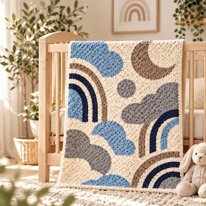 May include: A rectangular crochet baby blanket featuring a cream-colored background with a repeating pattern of dark blue, light blue, and brown rainbows, gray and light blue clouds, a brown crescent moon, and a small brown circle.