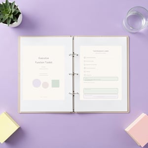 Op de afbeelding: Een open ringband met drie ringen met een Executive Function Toolkit-titelpagina aan de linkerkant en een Task Breakdown Ladder-werkblad aan de rechterkant. De pagina's zijn crèmekleurig met donkere tekst en geometrische vormen.
