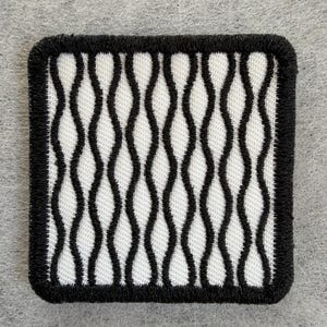 May include: A square embroidered patch featuring a repeating pattern of vertical black wavy lines against a white background, finished with a thick black stitched border around the entire perimeter of the square fabric piece.