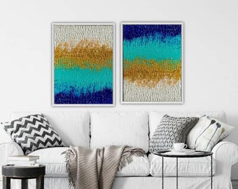May include: Two rectangular wall art pieces featuring heavy impasto texture. The left piece displays horizontal bands of white, gold, turquoise, and dark blue. The right piece features horizontal bands of dark blue, turquoise, gold, and white.