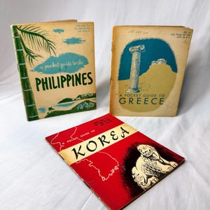 May include: Three vintage softcover booklets titled A Pocket Guide to the Philippines, A Pocket Guide to Greece, and A Pocket Guide to Korea. The Philippines guide features a palm tree, the Greece guide shows a column, and the Korea guide displays a map.
