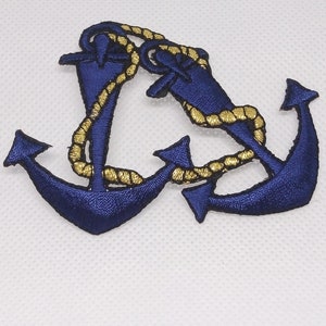 May include: A blue embroidered anchor with a gold rope design. The anchor is a nautical symbol and is often used in maritime decor.