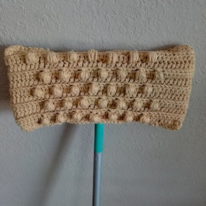 May include: A beige crocheted mop head with a textured bobble stitch pattern. The mop head is attached to a teal blue mop handle.