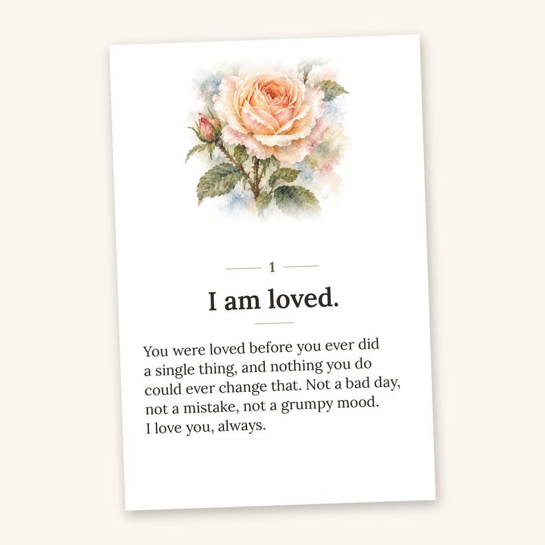 May include: A rectangular card featuring a watercolor illustration of a peach-colored rose with green leaves at the top. Below the rose, the number 1 is centered above the text I am loved. The card includes a paragraph of text starting with You were loved before you ever did a single thing, and nothing you do could ever change that. Not a bad day, not a mistake, not a grumpy mood. I love you, always.