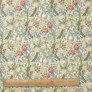 Puede incluir: Una tela de color crema con un patr&oacute;n repetitivo de lirios estilizados, hojas y flores en tonos de verde, amarillo, rojo y azul.
