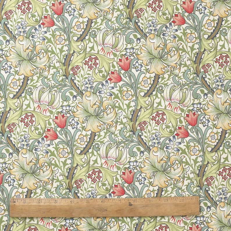 Puede incluir: Una tela de color crema con un patr&oacute;n repetitivo de lirios estilizados, hojas y flores en tonos de verde, amarillo, rojo y azul.