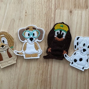 May include: Four felt finger puppets of cartoon dogs. The puppets are brown, white, tan, and black with embroidered details. The puppets are all smiling and have different facial expressions.