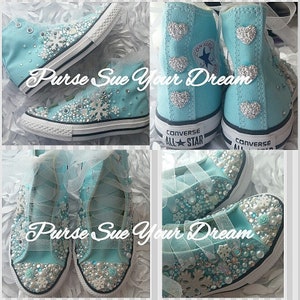 May include: Light blue high-top sneakers featuring white snowflake embellishments, silver heart-shaped accents on the heels, and clear rhinestones. The shoes have white rubber soles, white laces, and the text "Purse Sue Your Dream" overlaid.