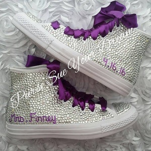 May include: A pair of high-top sneakers completely covered in clear rhinestones with deep purple satin ribbon laces. The text "Purse Sue Your Dream" is written in cursive, and the text "Mrs. Finney" and "4.16.16" are in purple script.