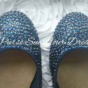 May include: A pair of round-toe flats completely covered in small, dark blue rhinestones. The interior of the shoes features a tan lining. The text "Purse Sue Your Dream" is overlaid in white script across the center of the two shoes.