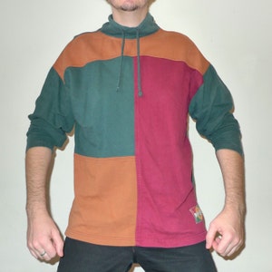 May include: A long-sleeved sweatshirt with a high neck and a color block design. The sweatshirt is made of a soft, comfortable fabric and features a green, brown, and burgundy color scheme.