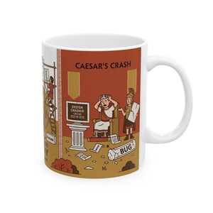 Peut inclure: Un mug en céramique blanche illustré d'un dessin intitulé CAESAR'S CRASH. On y voit un personnage romain en toge se tenant la tête devant un écran affichant SYSTEM CRASHUS Error 1111-0-1111, entouré de parchemins marqués error.