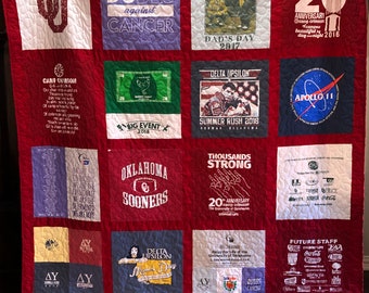 May include: A red quilt made from a variety of t-shirts. The quilt features a variety of designs and logos, including the University of Oklahoma logo, the words "Dudes Against Cancer", and the words "Delta Upsilon".