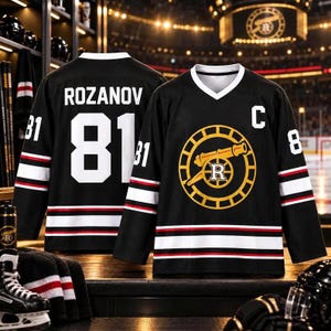 May include: A black hockey jersey featuring the name ROZANOV and the number 81 in white on the back. The front displays a yellow circular logo with a cannon and the letter R, a white letter C, and white number 81 on the sleeves.