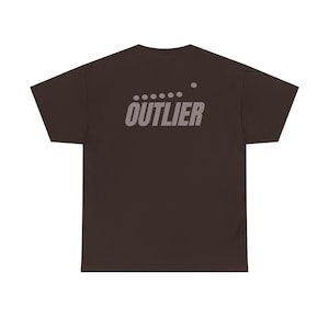 Op de afbeelding: Een donkerbruin t-shirt met korte mouwen en het woord OUTLIER in een lichtgrijs schreefloos lettertype op de bovenrug. Boven de tekst staat een horizontale rij van vijf kleine grijze stippen met daarboven nog een enkele stip.