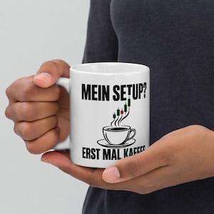 Może przedstawiać: Biały ceramiczny kubek z czarnym napisem "MEIN SETUP?" u góry i "ERST MAL KAFFEE" u dołu. Pomiędzy napisami znajduje się czarny rysunek filiżanki kawy, z której unosi się para w kształcie wykresu świecowego giełdowego.