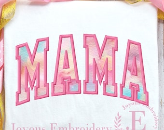 May include: Pink "MAMA" embroidery design with a watercolour effect. The design is in a collegiate font style with a pink outline. The design is on a white fabric background.