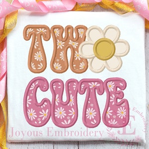 May include: Embroidered design featuring the words "The Cute" in a retro style with a daisy pattern. The letters are outlined in pink and brown and filled with a white daisy pattern.