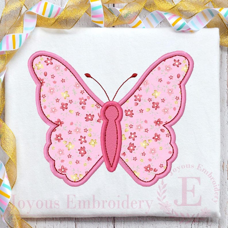 May include: Pink butterfly applique with a floral pattern. The butterfly has a pink body and is outlined in a darker pink. The butterfly is on a white background.