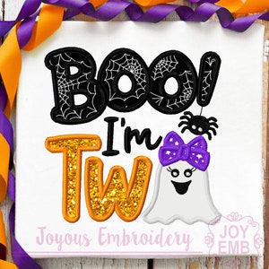 May include: White Halloween-themed design with the words "BOO! I'm Tw" in black, orange, and gold glitter lettering. A ghost with a purple bow and a spider complete the design. The words "Joyous Embroidery" are at the bottom.