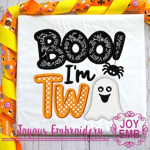 May include: White t-shirt with the text "BOO! I'm Tw" in black and orange. The word "BOO" is in a black decorative font, and a black spider hangs from the exclamation point. A white ghost with a smiling face is also featured.