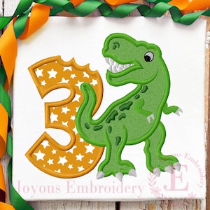 May include: A green dinosaur with a toothy grin stands next to a large orange number three with white stars. The number is slightly torn on the left side. The dinosaur has a green body with brown spots and white claws. The background is white.